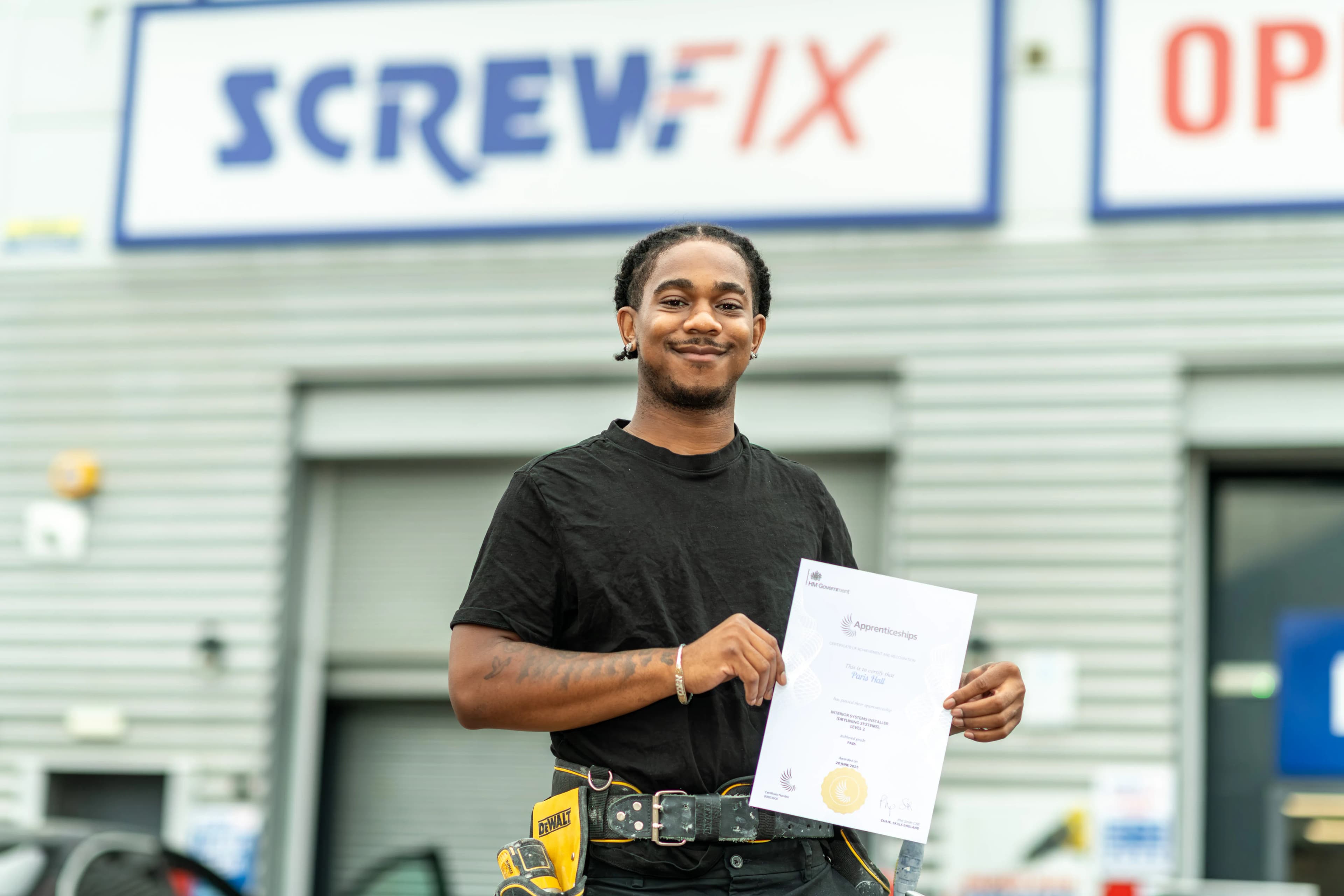 TrAC apprentice holding his apprenticeship certificate outside a Screwfix store